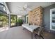 Covered patio featuring exposed brick wall, ceiling fan, table with chairs, and view of landscaped backyard at 9912 Pine Leaf Ln, Dade City, FL 33525