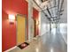 Hallway featuring concrete floors, exposed ceilings, and vibrant red walls, leading to individual units in the building at 101 S 12Th St # 318, Tampa, FL 33602