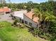 Landscaped front yard with mature palm trees, lush lawn, and home featuring a tile roof at 107 Seville N Ct, Plant City, FL 33566