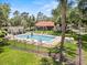 Community pool with people swimming, surrounded by lounge chairs, greenery and fencing for a serene outdoor experience at 107 Seville N Ct, Plant City, FL 33566