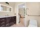 Modern bathroom featuring dark wood vanity with lighted mirror and wood-look tile flooring at 163 Shell Falls Dr, Apollo Beach, FL 33572
