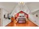Charming bedroom with red accent wall, dormer windows, hardwood floors, and bench at the foot of the bed at 607 N Merrin St, Plant City, FL 33563