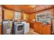 Functional laundry room with wooden ceiling and walls, includes washer, dryer, and storage at 607 N Merrin St, Plant City, FL 33563