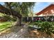 Charming backyard garden featuring a brick path, mature tree, and repurposed bathtub planter with decorative accents at 2872 Hammock Dr, Plant City, FL 33566