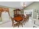 Elegant dining room features large table with seating for ten, decorative chandelier, and double doors to patio at 2872 Hammock Dr, Plant City, FL 33566