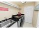 This laundry room has a stainless steel sink, modern washer and dryer, and black countertop with white storage space at 2872 Hammock Dr, Plant City, FL 33566