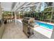 This outdoor kitchen features a stainless steel grill, and overlooks the pool and landscaped yard at 2872 Hammock Dr, Plant City, FL 33566