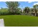 A well-manicured backyard, featuring lush green grass, mature trees, and a wooden fence for privacy at 1018 Briarwood Ave, Tampa, FL 33613