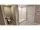 Bathroom featuring a tiled shower, toilet, and tiled flooring, with a white door adding a clean and modern look at 3188 Nubbin Ridge Ln, Zephyrhills, FL 33540