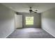 Cozy bedroom with carpeted floors, a ceiling fan, and a window overlooking the backyard at 3188 Nubbin Ridge Ln, Zephyrhills, FL 33540
