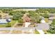 An aerial view captures the stucco home amidst mature trees, landscaped yard, and lake backdrop at 5370 Boxtree Ct, Dade City, FL 33523