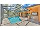 Screened-in pool area features an outdoor kitchen and travertine tile flooring at 5370 Boxtree Ct, Dade City, FL 33523
