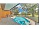 Outdoor screened-in pool with patio area, outdoor kitchen, and lush green landscaping at 5370 Boxtree Ct, Dade City, FL 33523