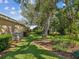 Backyard with lush lawn, mature trees, and colorful flowers creating a serene outdoor space at 5903 Cachette De Riviera Ct, New Port Richey, FL 34655