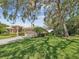 Home with manicured lawn, mature trees, and lush landscaping enhancing its curb appeal at 5903 Cachette De Riviera Ct, New Port Richey, FL 34655