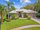 Inviting single-story home with a well-manicured lawn, lush landscaping, and a pristine tile roof at 5903 Cachette De Riviera Ct, New Port Richey, FL 34655