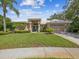 Beautifully landscaped front exterior of the home with a manicured lawn and palm trees at 5903 Cachette De Riviera Ct, New Port Richey, FL 34655