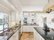 Bright kitchen featuring white cabinets, granite countertops, and stainless steel appliances, opening to the living room at 5903 Cachette De Riviera Ct, New Port Richey, FL 34655
