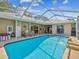 A screened pool offers clear water, an outdoor kitchen and a peaceful backyard view at 5903 Cachette De Riviera Ct, New Port Richey, FL 34655