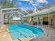 A screened pool offers clear water, an outdoor kitchen and a peaceful backyard view at 5903 Cachette De Riviera Ct, New Port Richey, FL 34655