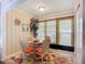 Cozy breakfast nook with circular glass table, bright orange chair cushions, and views of the greenery outside at 6012 28Th W St, Bradenton, FL 34207