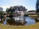 Picturesque view of a tranquil pond with a fountain surrounded by mature trees at 6012 28Th W St, Bradenton, FL 34207