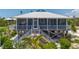 Charming raised waterfront home featuring a screened porch, white railings, and tropical landscaping at 9712 Little Gasparilla Is, Boca Grande, FL 33921