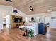 Open-concept living room boasts wood floors, ceiling fan, a large TV, and white walls at 9712 Little Gasparilla Is, Boca Grande, FL 33921