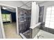 Stylish bathroom featuring a glass-enclosed shower, soaking tub, and natural light, adjacent to a bedroom at 16804 Hawkridge Rd, Lithia, FL 33547
