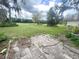 Expansive backyard featuring mature trees and a partially paved patio area at 1909 Masters Way, Plant City, FL 33566