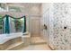 Bright bathroom with soaking tub, walk-in shower with glass door, nature views, and patterned wallpaper at 1909 Masters Way, Plant City, FL 33566