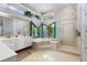 Bright bathroom with white cabinets, soaking tub, a walk-in shower, and nature views through a large window at 1909 Masters Way, Plant City, FL 33566