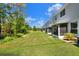 Townhouse backyard with green grass, screened patio, and a view of the community green space and treeline at 34852 Teeview Ln, Zephyrhills, FL 33541