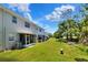 Townhouse backyard with lush green grass, screened patio, and a view of the lake and treeline in the distance at 34852 Teeview Ln, Zephyrhills, FL 33541