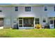 The back of the townhouse includes a screened in porch and a small backyard space with green grass and a few plants at 34852 Teeview Ln, Zephyrhills, FL 33541