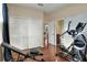 The exercise room features an elliptical, weight bench, and dark hardwood floors leading to bedroom and bathroom at 3507 Autumn Glen Dr, Valrico, FL 33596