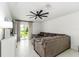 Open living room with neutral toned sofa, tile floors, modern fan, and sliding glass doors to backyard at 4035 Radiant Mountain Dr, Plant City, FL 33565