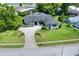 Aerial view of a single-story home with a large driveway, a lush lawn, and mature trees at 8721 Latham Ln, Hudson, FL 34667