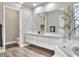 Bright bathroom features wood look floors, long vanity, a large mirror, and soaking tub at 8721 Latham Ln, Hudson, FL 34667