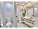 Bathroom showcases vanity, toilet, and doorway, enhanced by gray wood-look tile flooring and bright, neutral paint at 8721 Latham Ln, Hudson, FL 34667