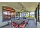 Outdoor screened lanai with large windows providing natural light, a ceiling fan, and a patio table with red cushions at 8721 Latham Ln, Hudson, FL 34667