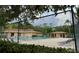 View of community pool with lounging chairs behind chain link fence and surrounded by mature trees at 11704 Raintree Village Blvd # B, Temple Terrace, FL 33617