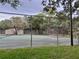 Outdoor tennis court surrounded by chain link fence and mature trees at 11704 Raintree Village Blvd # B, Temple Terrace, FL 33617