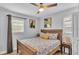 Cozy bedroom with a wood frame bed, decorative pillows, two windows, and a ceiling fan at 1603 N Park Rd, Plant City, FL 33563