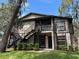 Two-story condo featuring neutral paint, black trim and railings, green bushes, and well-maintained landscaping at 4022 Tumble Wood Trl # 101, Tampa, FL 33613