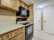 Kitchen showcasing wooden cabinetry, black appliances, and tiled flooring at 4022 Tumble Wood Trl # 101, Tampa, FL 33613