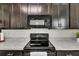 Close up of modern kitchen with dark cabinets, white countertops, and stainless steel appliances at 503 Arbequina Ct, Plant City, FL 33566