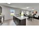 View of kitchen with island and sink, showing dining and living area with natural lighting at 503 Arbequina Ct, Plant City, FL 33566