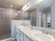 Modern bathroom with double vanity, granite countertops, tiled shower with glass door, and contemporary fixtures at 35494 Coventry Fields Loop, Zephyrhills, FL 33541