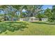 Wide shot of backyard with a spacious lawn, mature trees, trampoline, and storage shed at 4818 Huron St, Zephyrhills, FL 33541